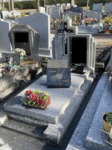 Tombeau en marbre avec croix, fleurs colorées sur un cimetière bien entretenu.